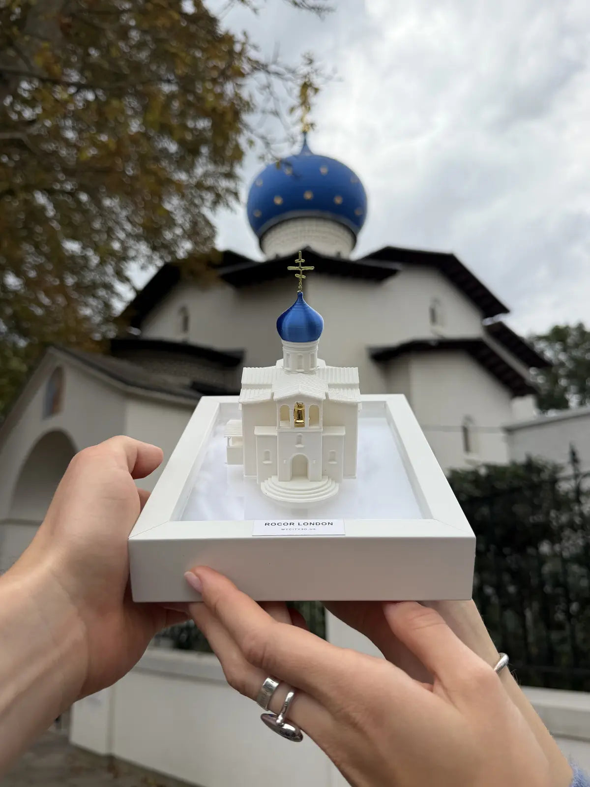 Hand-held miniature ROCOR church model photographed in front of the real church
